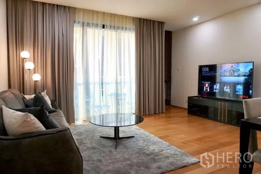 Condominium for rent in Khlong Toei, Bangkok - Another angle of the living room with sofa, round table and balcony drapes.