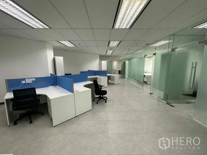 Office Space for rent - Open cubicle area with blue dividers facing frosted glass offices.