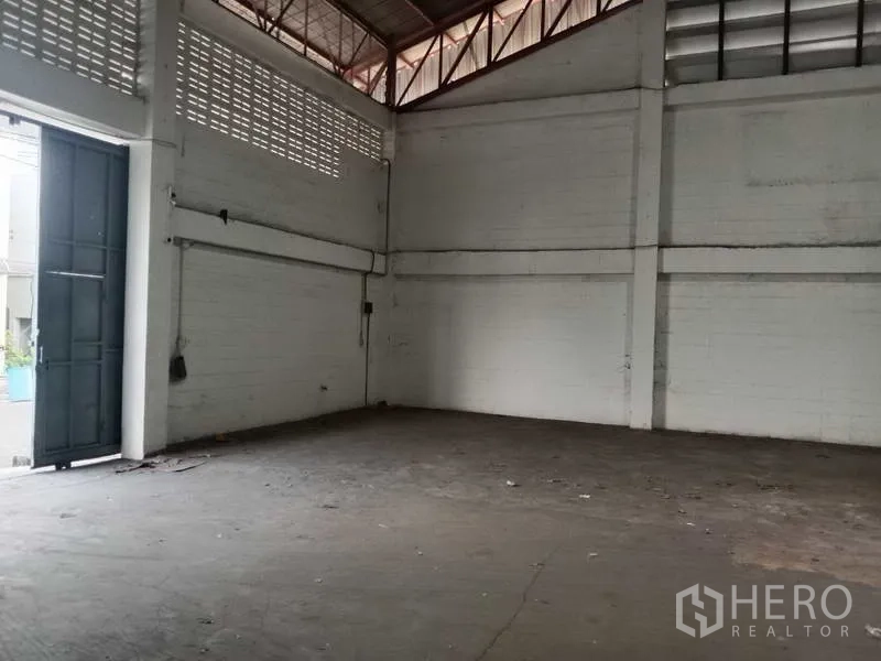 Factory for rent in Samut Prakan - Corner of production area beside tall loading door and vented block walls.