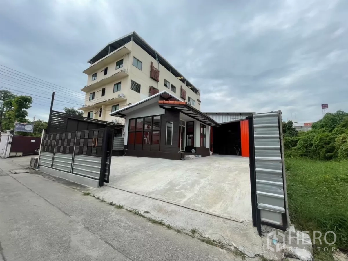 Warehouse for rent in Khlong Toei, Bangkok - Street view of the wide sliding gate and driveway leading to the office and warehouse.