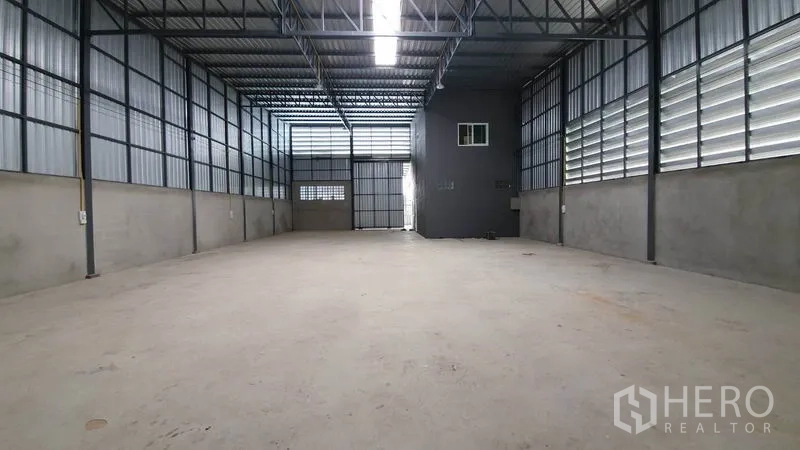 Warehouse for rent in Lam Luk Ka, Pathum Thani - Wide-angle view of the warehouse hall showing steel framing, windows and concrete flooring.