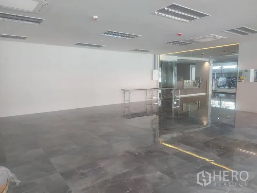Retail Space for rent - Open retail space showing shiny tiled floors, ceiling AC vents and glass entryway.