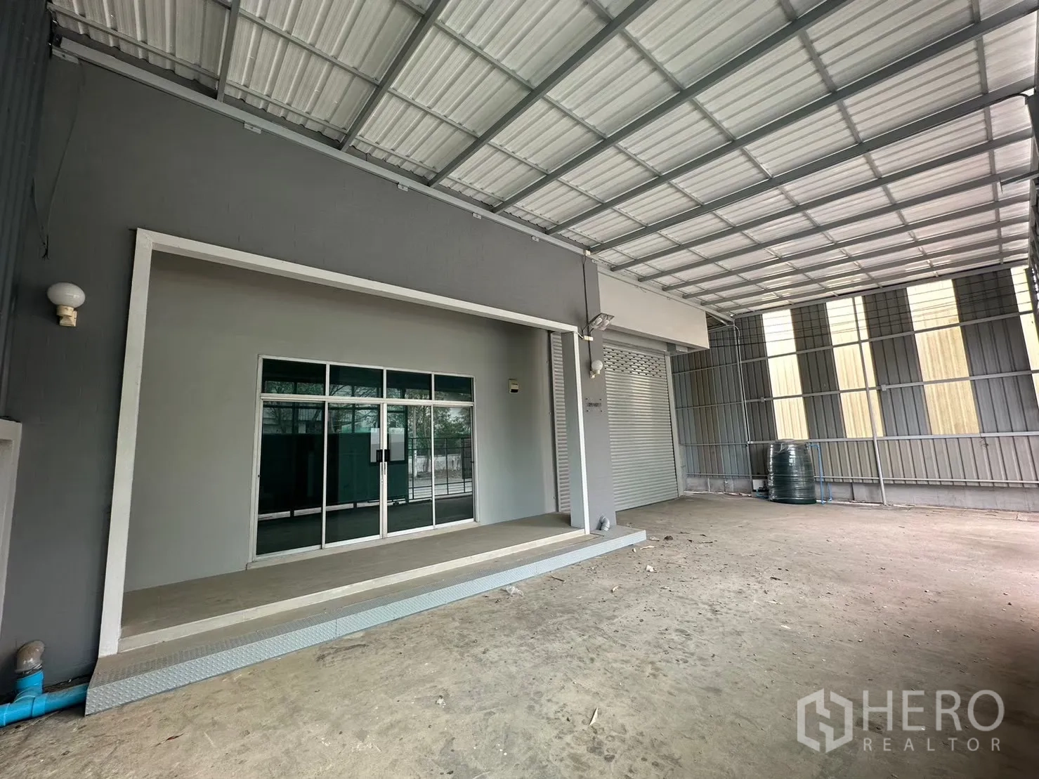 Factory for rent in Bang Bua Thong, Nonthaburi - Covered loading area with glass entry and a roller shutter.
