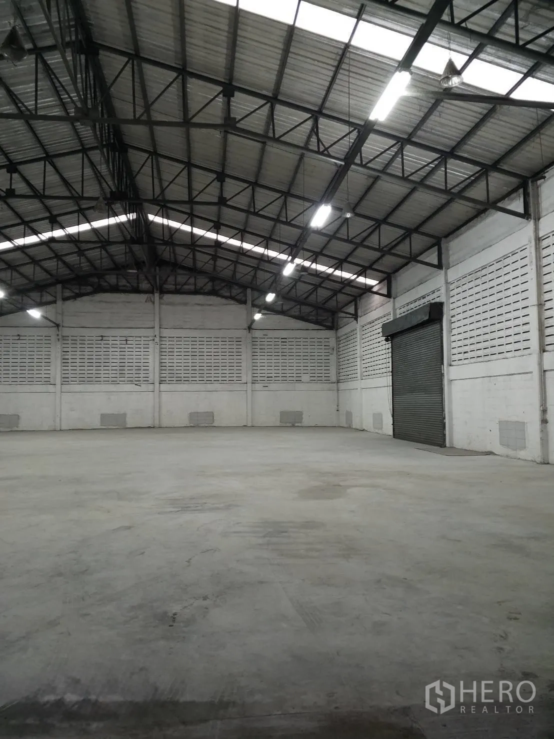 โกดัง for rent in Min Buri, Bangkok - พื้นที่โกดังเปิดโล่ง แสดงโครงหลังคาแข็งแรงและประตูม้วนทางเข้า