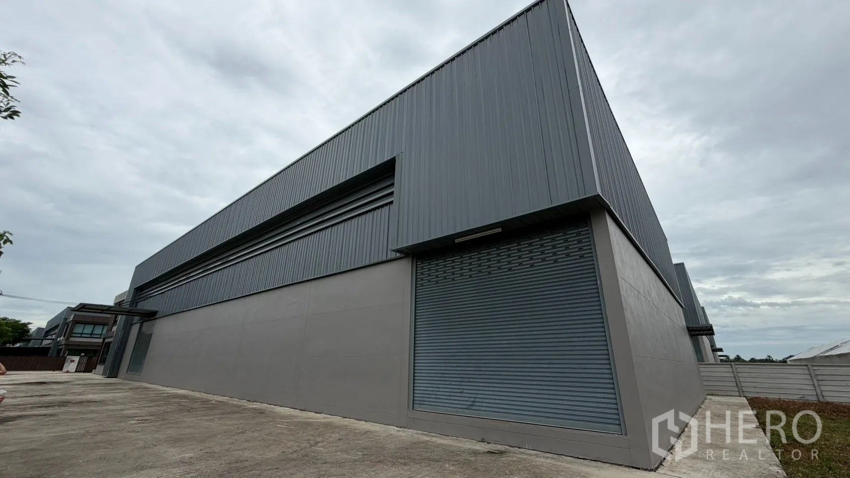 Factory for sale in Bang Len, Nakhon Pathom - Steel-clad warehouse elevation with wide roller shutter door.