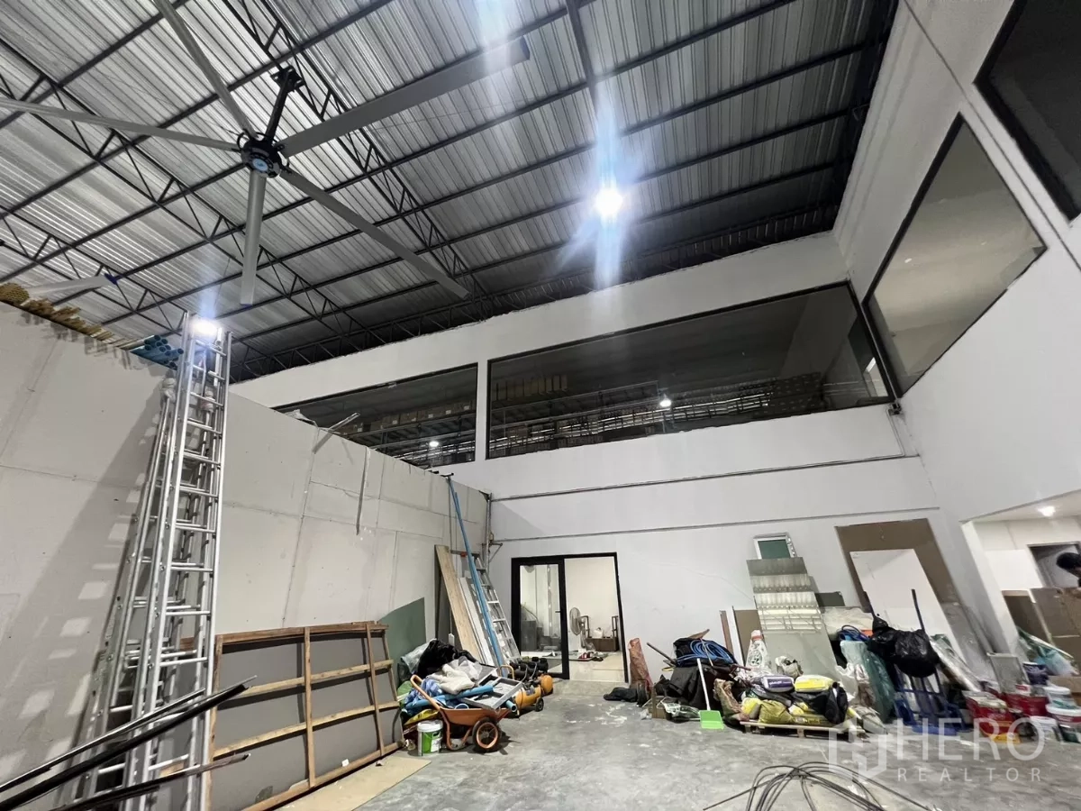 Warehouse for rent or sale in Lat Krabang, Bangkok - High-ceiling warehouse bay with metal roof, mezzanine windows and an industrial ceiling fan.