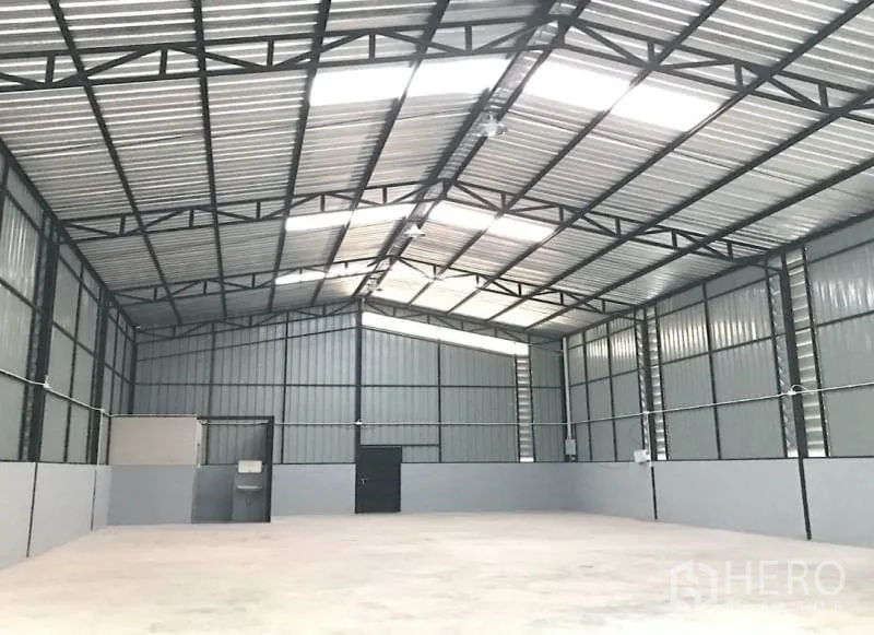 Warehouse for rent in Chatuchak, Bangkok - Bright storage hall with metal walls, skylight panels and a large sliding door.