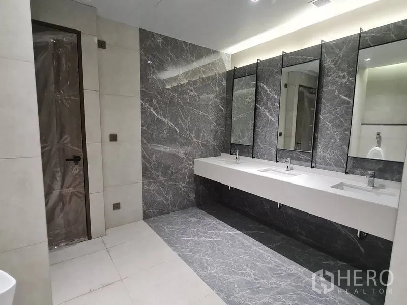 Office Space for rent - Spacious restroom with marble feature wall, long countertop and multiple mirrors and basins.