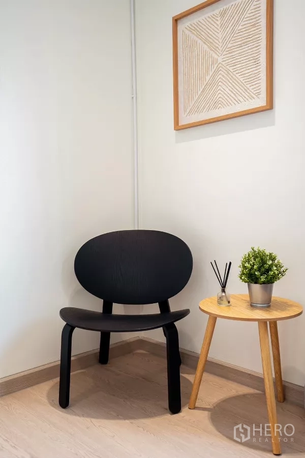 Detached House for rent in Huai Khwang, Bangkok - Minimal corner seating with a black accent chair and small side table.