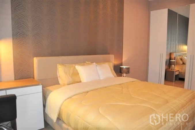 Condominium for rent or sale in Watthana, Bangkok - Cozy bedroom with upholstered bed, bedside lamps, and wardrobe.