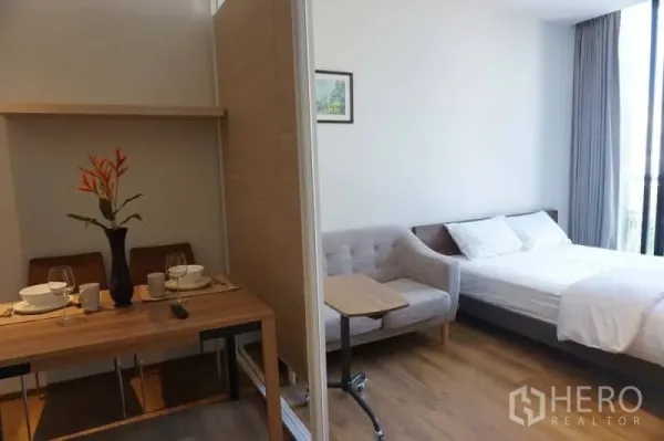 Condominium for rent or sale in Khlong Toei, Bangkok - Dining nook for two beside sofa and bed, divided by a partial partition in the condo.