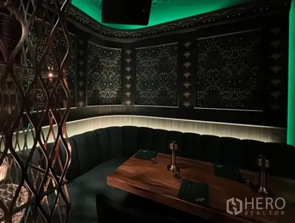 Retail Space for rent in Bang Rak, Bangkok - Moody private booth with curved velvet banquette, wood table and patterned wall panels under green accent lighting.