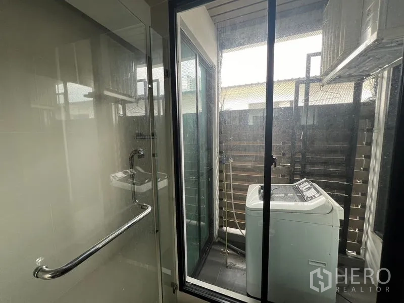 Townhouse for rent or sale in Khlong Toei, Bangkok - Utility balcony with a washing machine and sliding glass doors.