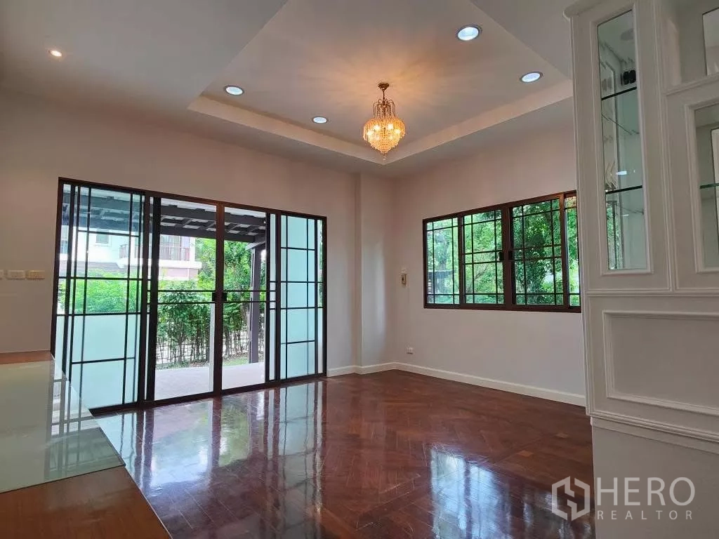 Detached House for rent or sale in Mueang Nonthaburi, Nonthaburi - Bright living room with parquet flooring, chandelier and wide sliding glass doors.