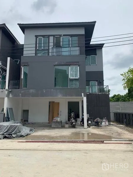 Detached House for sale in Prawet, Bangkok - Front view of a new three-storey house under construction with a carport and wide driveway.