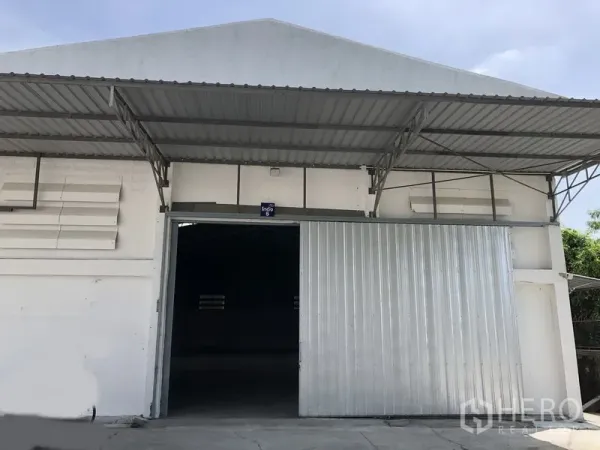 Warehouse for rent in Mueang Pathum Thani, Pathum Thani - Close-up of warehouse entrance featuring a tall sliding metal door and canopy.