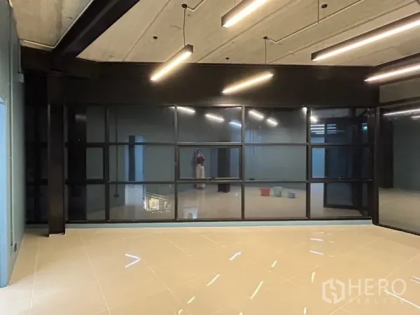 Office Space for rent in Chatuchak, Bangkok - Modern office room with a full wall of tinted grid windows, pendant linear lights and reflective porcelain flooring.