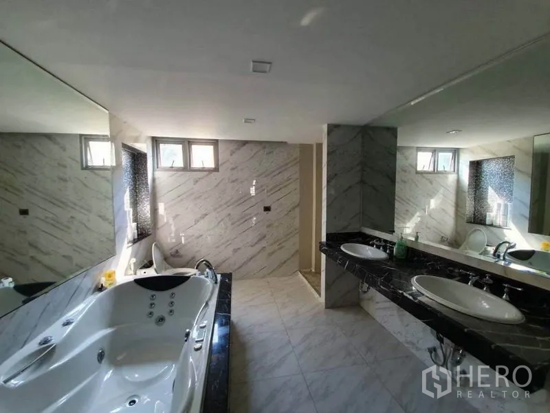 Office Space for rent in Khlong Toei, Bangkok - Modern bathroom with marble walls, double vanity and a whirlpool bathtub.