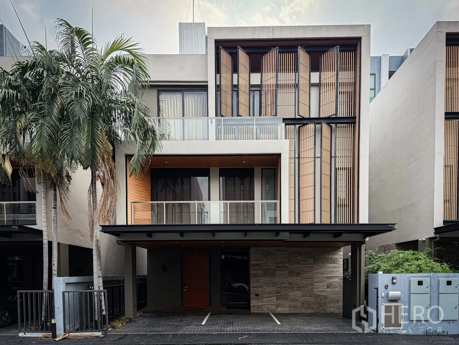 บ้านเดี่ยว for rent or sale in Lak Si, Bangkok - ด้านหน้าบ้านเดี่ยวสมัยใหม่ มีระเบียง ซันสกรีนแนวตั้ง และที่จอดรถมีหลังคา.