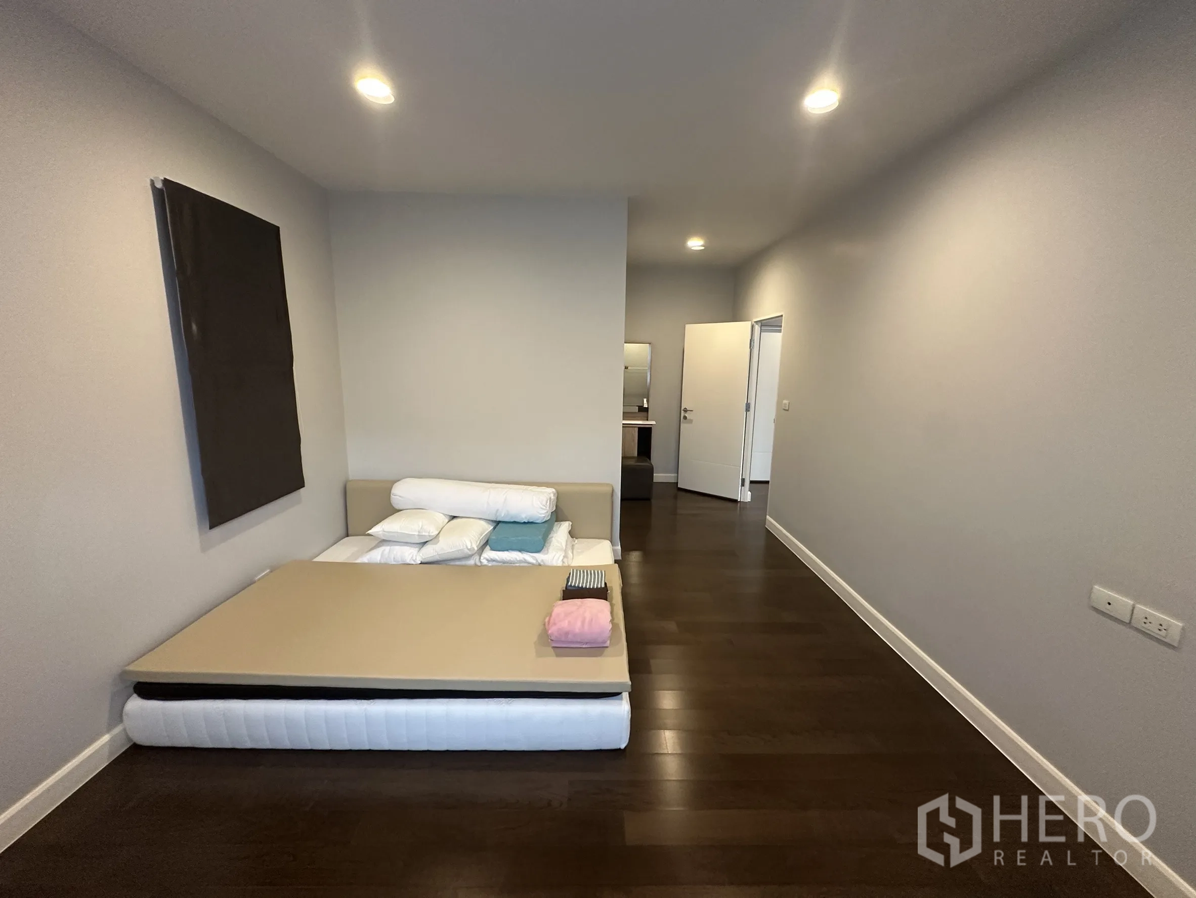 Detached House for rent in Lam Luk Ka, Pathum Thani - Spacious bedroom with low bed and ensuite beyond.