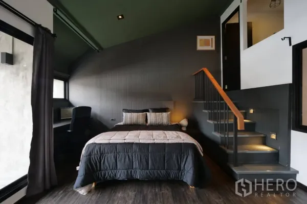 Townhouse for rent in Khlong Toei, Bangkok - Cozy dark-toned bedroom with built-in desk and staircase with step lights.
