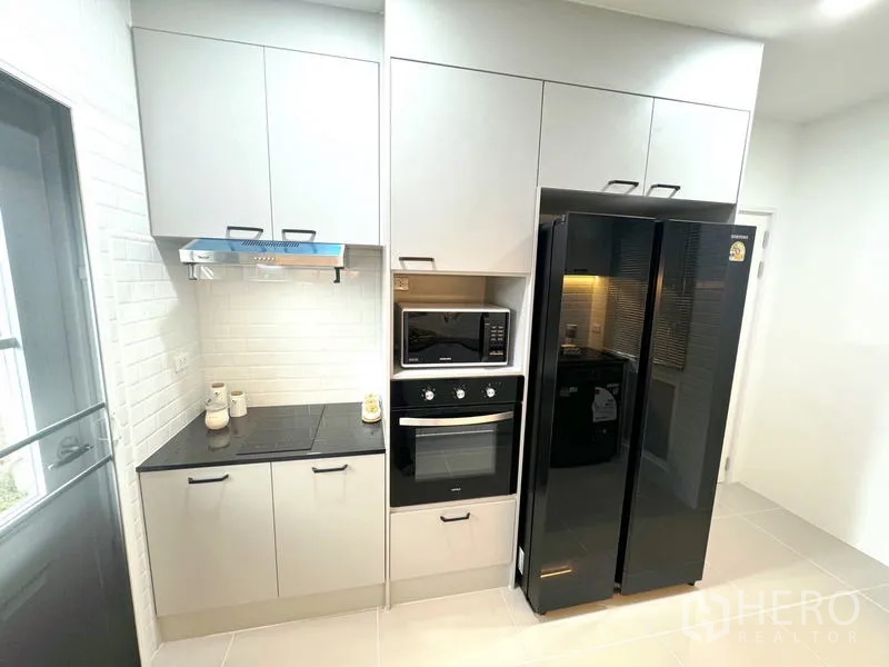 Detached House for rent - Compact kitchen wall with cooktop, oven, microwave and double-door fridge.