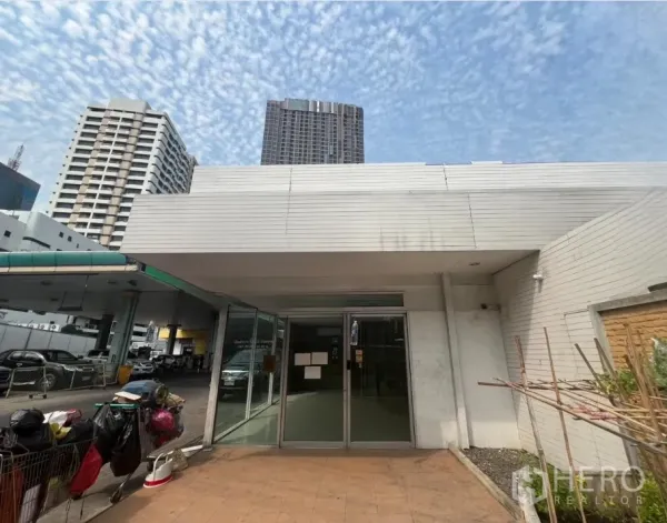 Retail Space for rent in Khlong Toei, Bangkok - Low-rise retail facade with wide canopy and high-rise towers in the background.