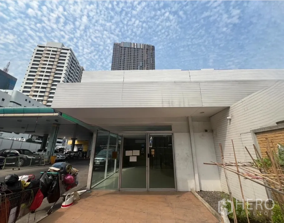 Retail Space for rent in Khlong Toei, Bangkok - Low-rise retail facade with wide canopy and high-rise towers in the background.