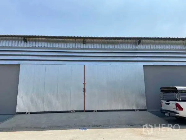 Warehouse for rent in Lam Luk Ka, Pathum Thani - Front elevation showing large steel sliding gate and driveway suitable for truck access.