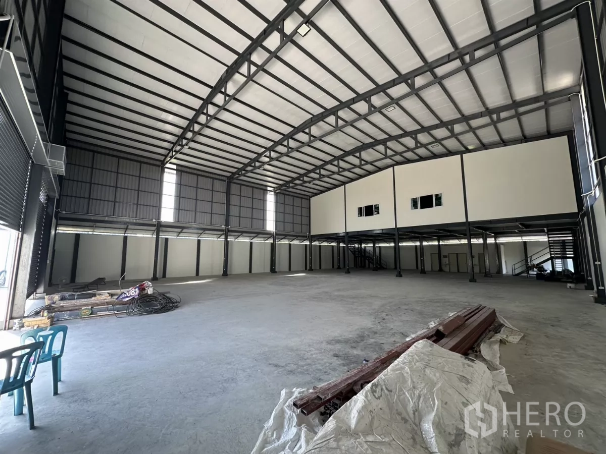 Warehouse for rent in Prawet, Bangkok - Spacious warehouse interior with high arched roof, steel beams and mezzanine office rooms.