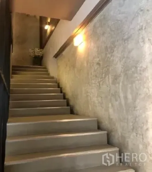 Retail Space for rent in Pathum Wan, Bangkok - Internal staircase with polished concrete walls and soft wall lights connecting retail floors.
