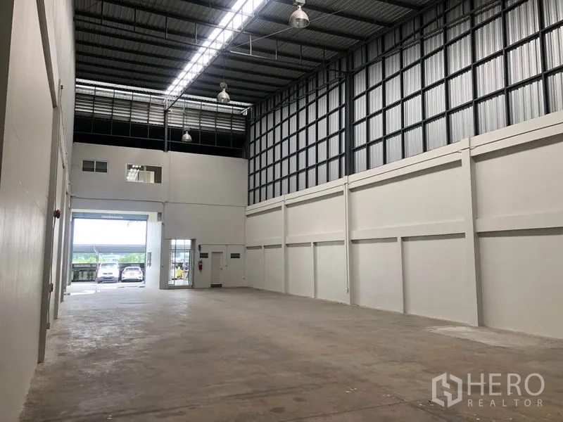 Factory for rent in Pak Kret, Nonthaburi - Side perspective of the warehouse showing ventilation panels and open roller door to parking.