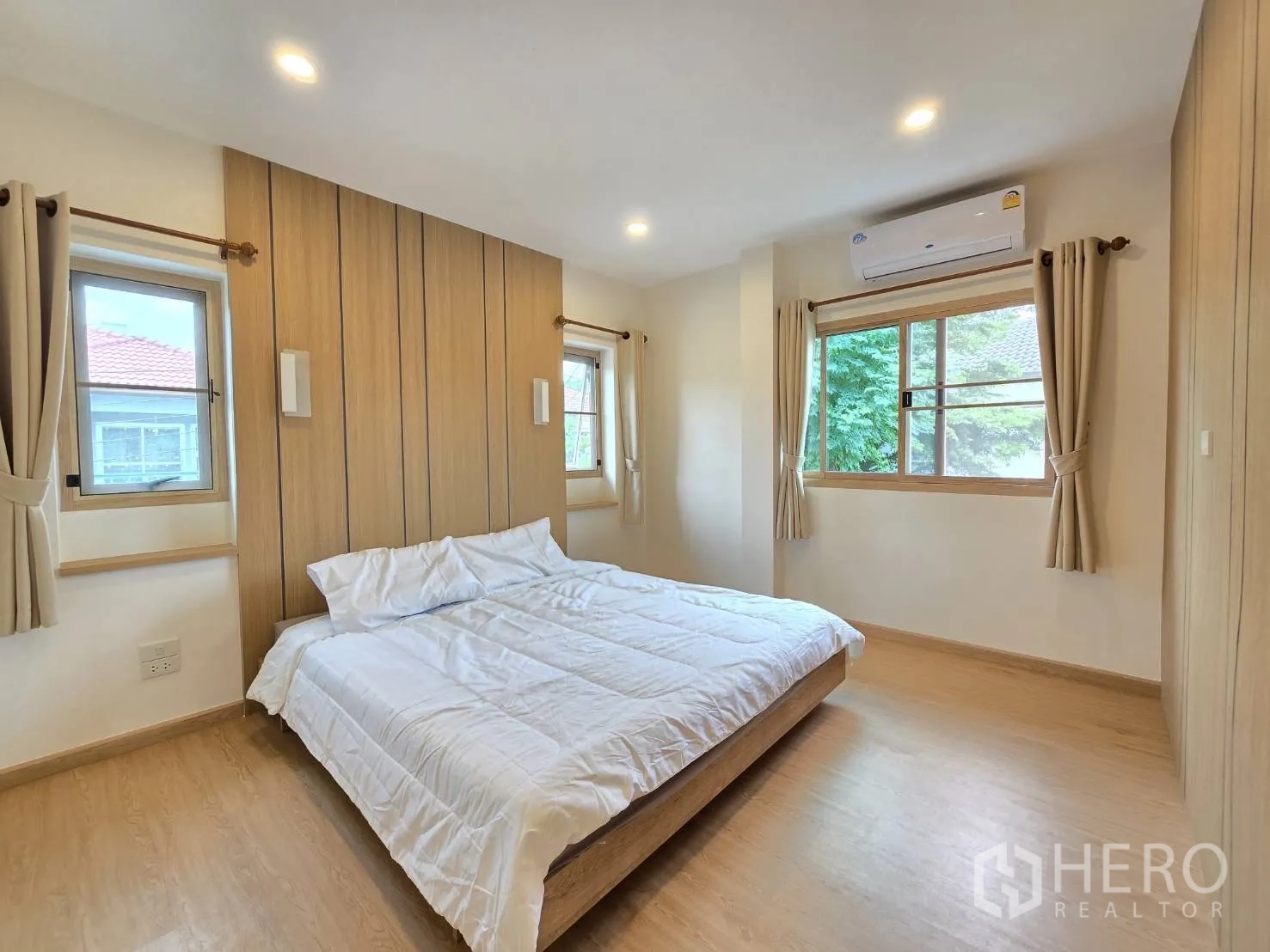 Detached House for sale in Suan Luang, Bangkok - Corner bedroom with three windows, air-conditioning and wood accent wall.