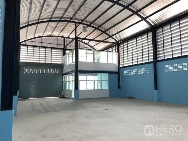 Factory for rent or sale in Bang Bua Thong, Nonthaburi - Spacious production hall with high arched steel roof and glass-enclosed mezzanine office.