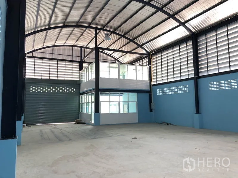 Factory for rent or sale in Bang Bua Thong, Nonthaburi - Spacious production hall with high arched steel roof and glass-enclosed mezzanine office.