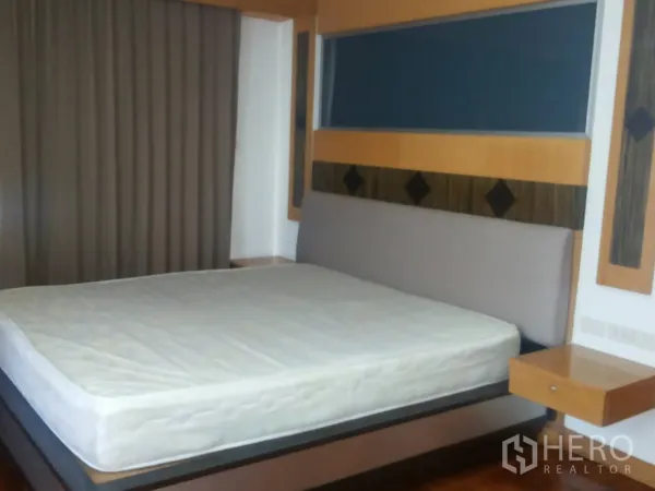 Apartment for rent in Khlong Toei, Bangkok - Bedroom with king bed, feature headboard, and full-length blackout curtains.