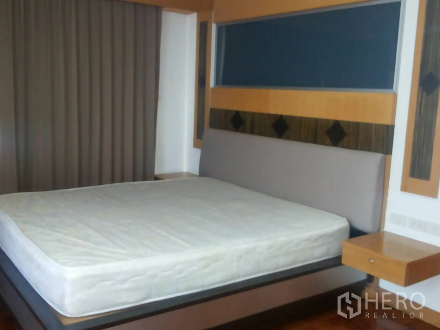Apartment for rent in Khlong Toei, Bangkok - Bedroom with king bed, feature headboard, and full-length blackout curtains.
