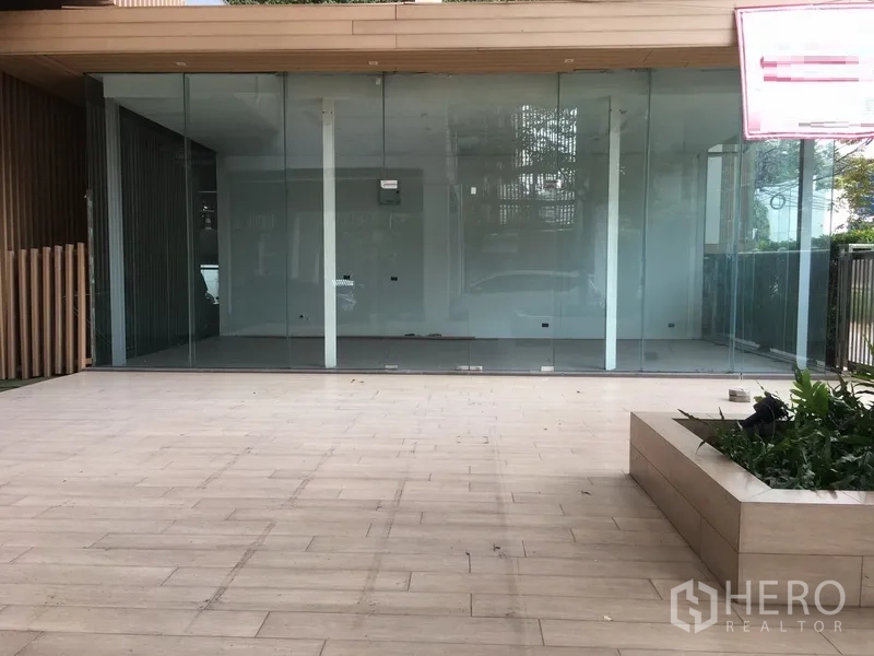Retail Space for rent in Watthana, Bangkok - Empty glass-front unit showing open-plan interior and wide patio with planter box.