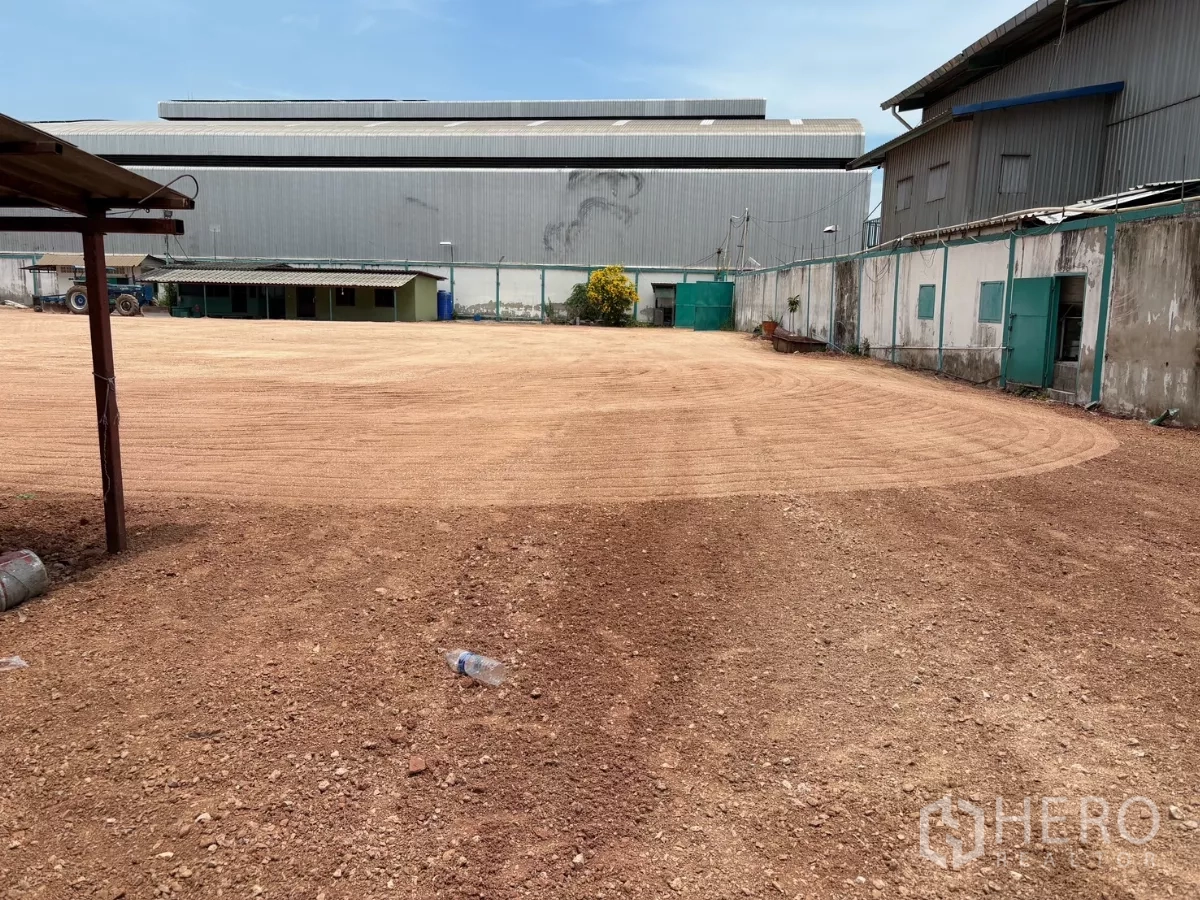 Factory for rent in Mueang Samut Sakhon, Samut Sakhon - Service yard between buildings with perimeter wall, outbuildings and green access doors.