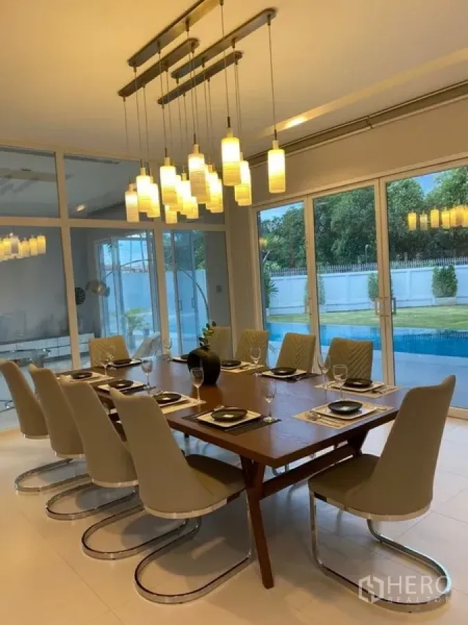 Detached House for rent in Suan Luang, Bangkok - Contemporary dining room with a long table, pendant lights and pool views through sliding glass doors