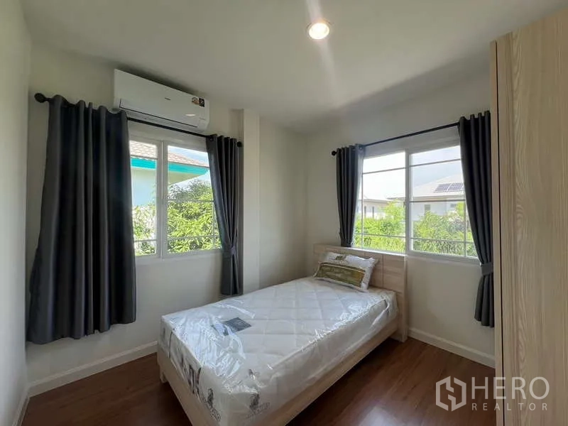 Detached House for rent in Bang Kapi, Bangkok - Single bedroom with two corner windows, air conditioner and laminate flooring.