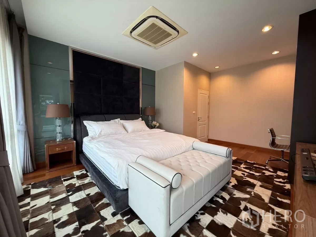 Detached House for rent or sale in Prawet, Bangkok - Primary bedroom with king bed, tall headboard and wood flooring.