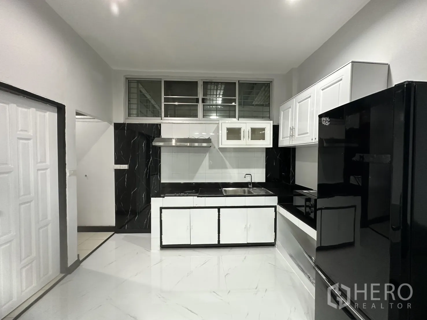 Home Office for rent in Khlong Toei, Bangkok - Black-and-white kitchen with upper cabinets, sink, hood, and refrigerator.