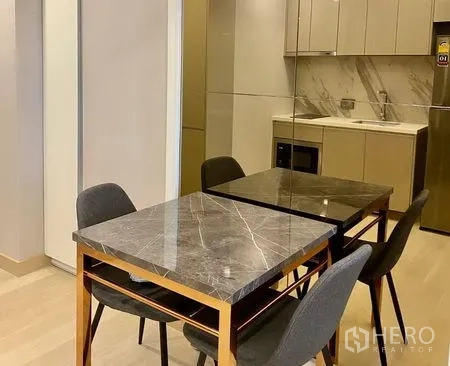 公寓 出租在Khlong Toei, Bangkok - 用餐区设石面餐桌与四把深色餐椅，旁有内置柜体。