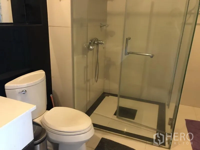 Condominium for rent in Pathum Wan, Bangkok - Modern bathroom with a glass-enclosed shower and white toilet.
