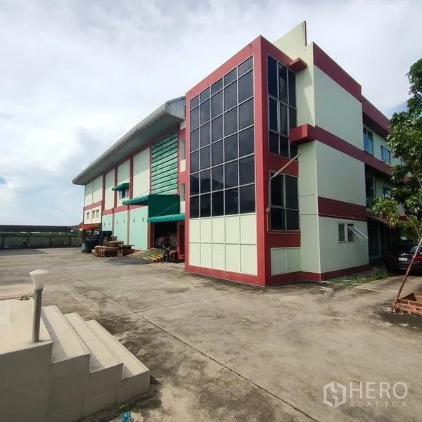 工厂 出租在Mueang Samut Sakhon, Samut Sakhon - 现代工厂外观，玻璃幕墙办公楼与宽阔混凝土场院。
