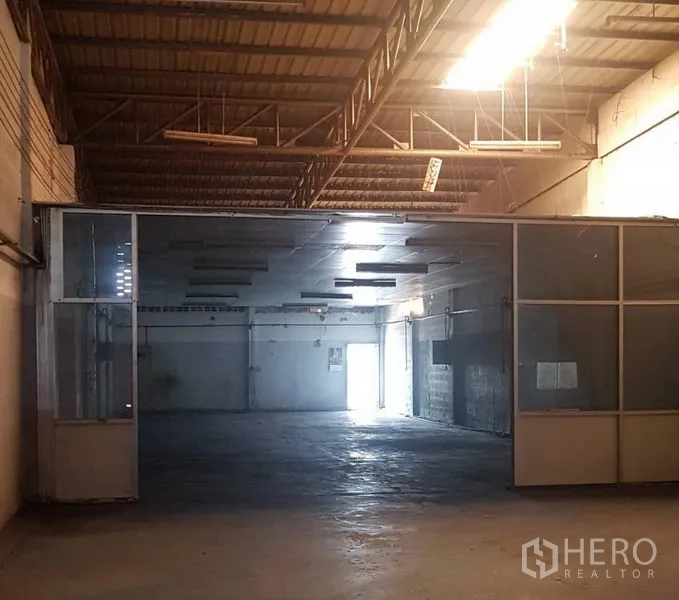 Warehouse for rent in Khlong Luang, Pathum Thani - Spacious warehouse floor with high steel-truss ceiling, concrete floor and glass-partitioned room.