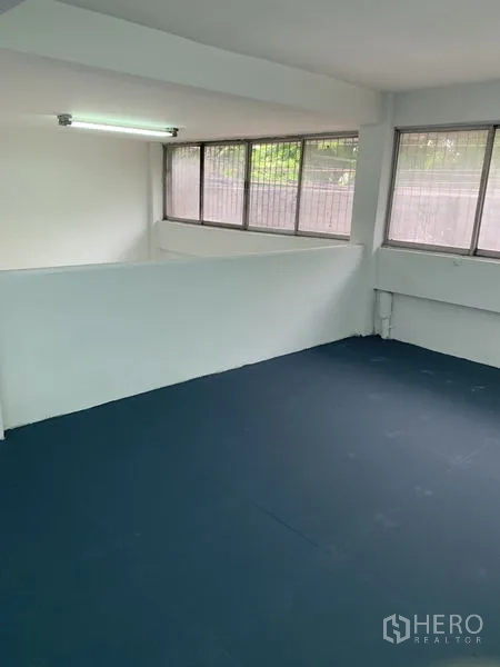 Shophouse for rent in Bang Na, Bangkok - Upper floor room with large corner windows and dark epoxy flooring.