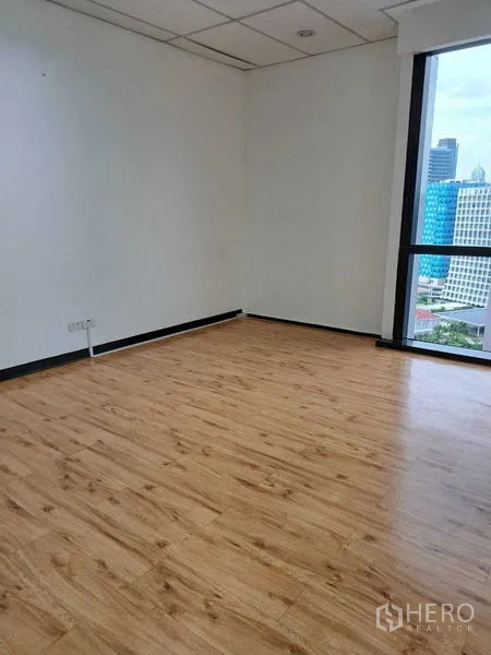 Office Space for rent in Bang Rak, Bangkok - Private corner room with wood-look flooring and a tall window overlooking the city.