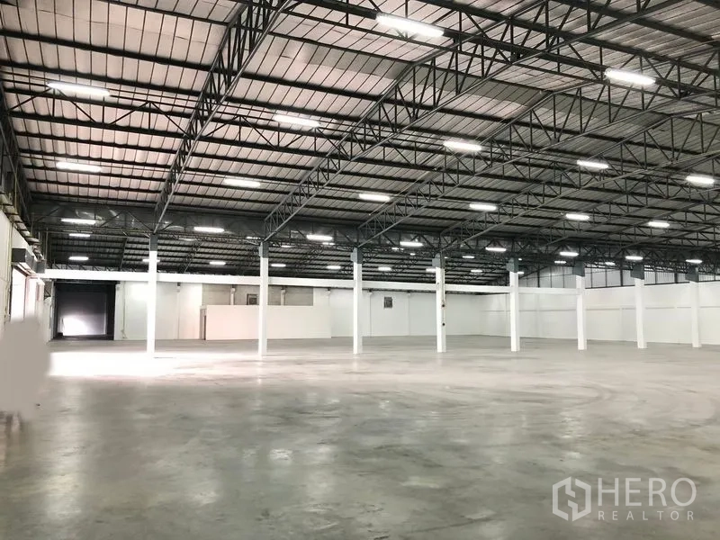 货栈 出租在Pak Kret, Nonthaburi - 大跨度仓库地面，多个作业湾，远端可见卷帘门入口。